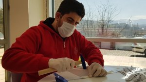 Ellerinde çekiç, delgeç ve perçinle siperlikli maske üretiyorlar